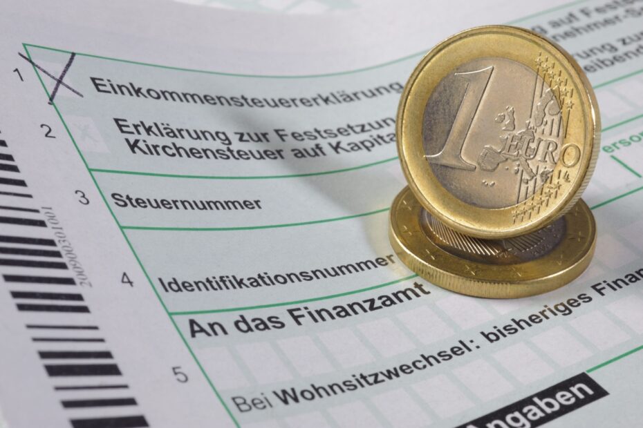 Ein Einkommensteuerformular mit einer Euro-Münze darauf, symbolisch für finanzielle und steuerliche Themen wie die Absetzung von Unterhaltszahlungen.